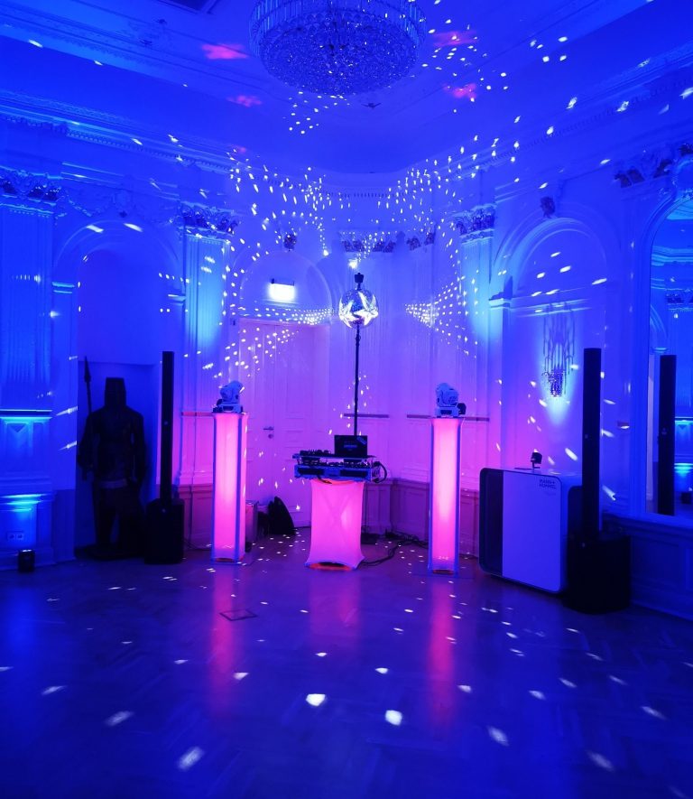 Bunte Lichter und Nebel in einem festlichen Raum mit DJ-Ausrüstung.
