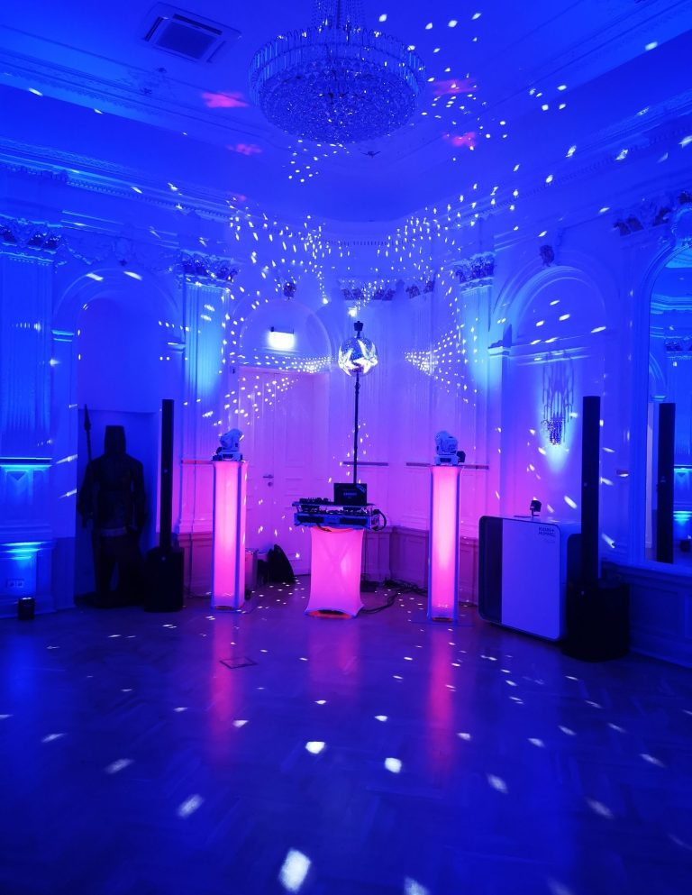 Bunte Lichter und Nebel in einem festlichen Raum mit DJ-Ausrüstung.