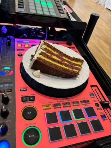 Ein Stück Schokoladenkuchen liegt auf einem DJ-Pult.