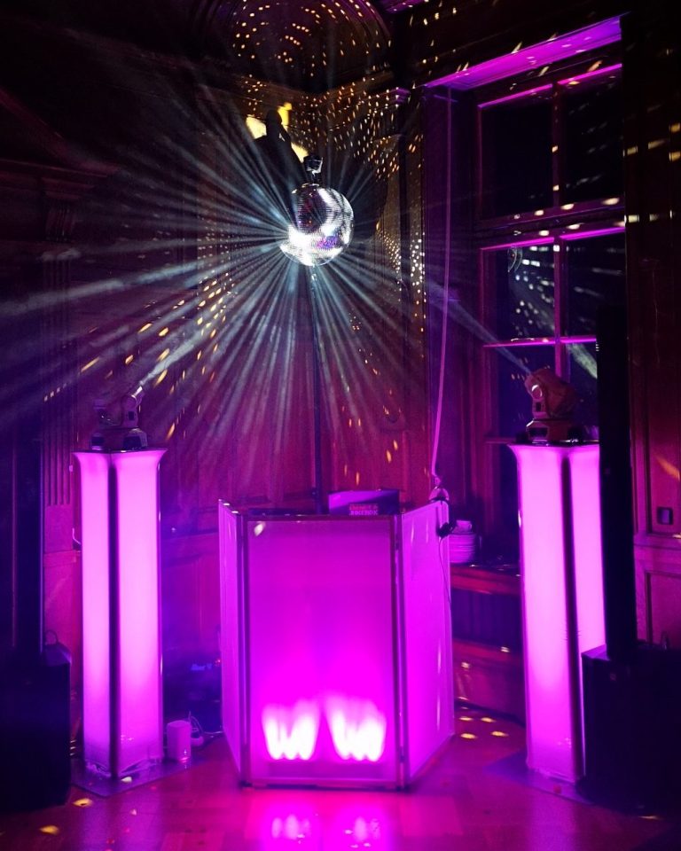 Bunte Discokugel reflektiert Licht in einem stilvollen Raum mit pinken Säulen.