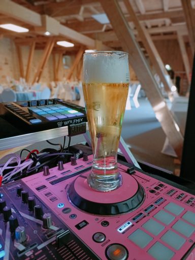 Ein Glas Bier steht auf einem pinken DJ-Pult in einem modernen Raum. Photo by DJ Mirko Anders
