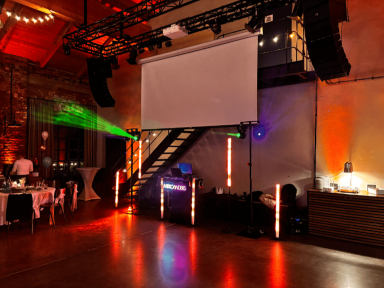 Veranstaltungsraum mit Lichtinstallationen und Projektor an der Wand.