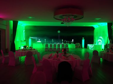 Eleganter Veranstaltungsraum mit grüner Beleuchtung und gedeckten Tischen. Photo by DJ Mirko Anders