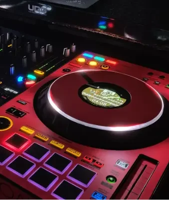DJ-Pult mit bunten Lichtern, Plattenspieler und elektronischen Steuerungen.
