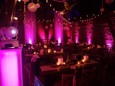 Elegant Veranstaltungsraum mit rosa Beleuchtung und festlich gedeckten Tischen. Photo by DJ Mirko Anders