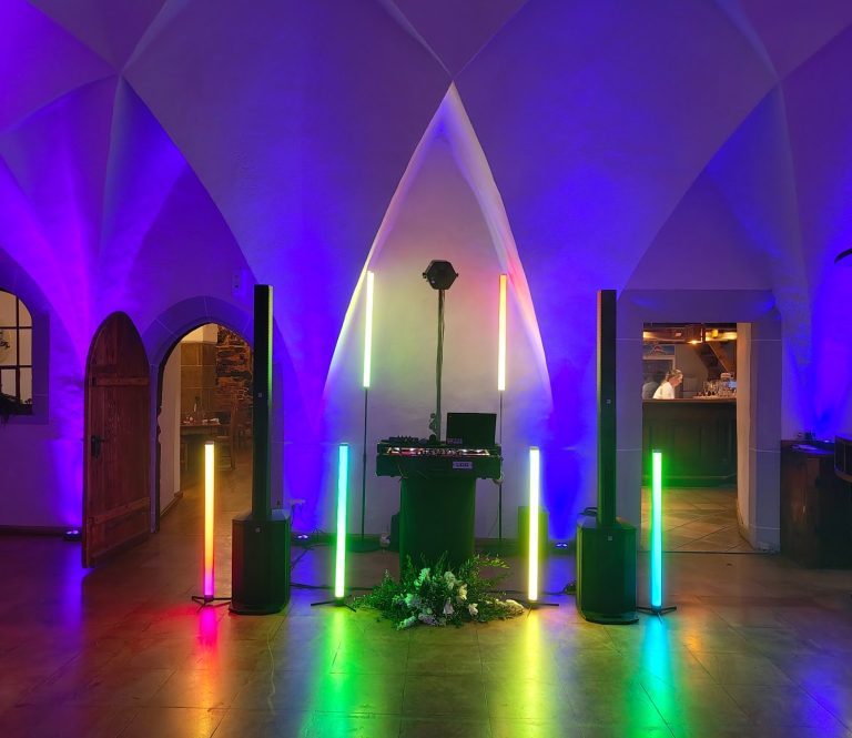 Farbenfrohe Beleuchtung in einem Raum mit Lautsprechern und einem DJ-Pult.