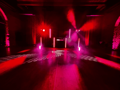 Dunkler Raum mit roten und pinken Lichtern, die eine festliche Atmosphäre erzeugen.