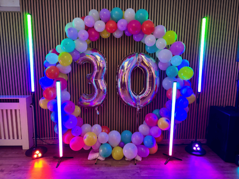 Party-Atmosphäre mit DJ und bunten Lichtern, Hintergrund beleuchtet in Blau und Grün.