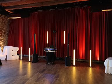 Bühne mit roten Vorhängen, Beleuchtung und Equipment für eine Veranstaltung. Photo by DJ Mirko Anders
