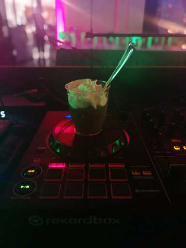 Ein Dessertbecher mit Sahne sitzt auf einem DJ-Pult mit bunten Lichtern. Photo by DJ Mirko Anders