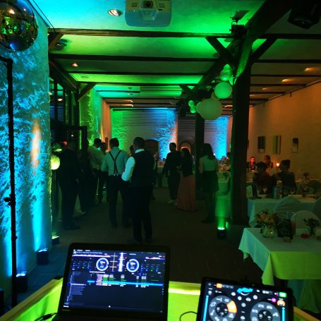 Ein DJ-Pult mit buntem Licht, Blick auf eine feierliche Veranstaltung. Photo by DJ Mirko Anders