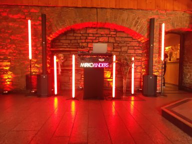 Stehtisch mit LED-Lichtern und Steinen, beleuchtet in roten Tönen.