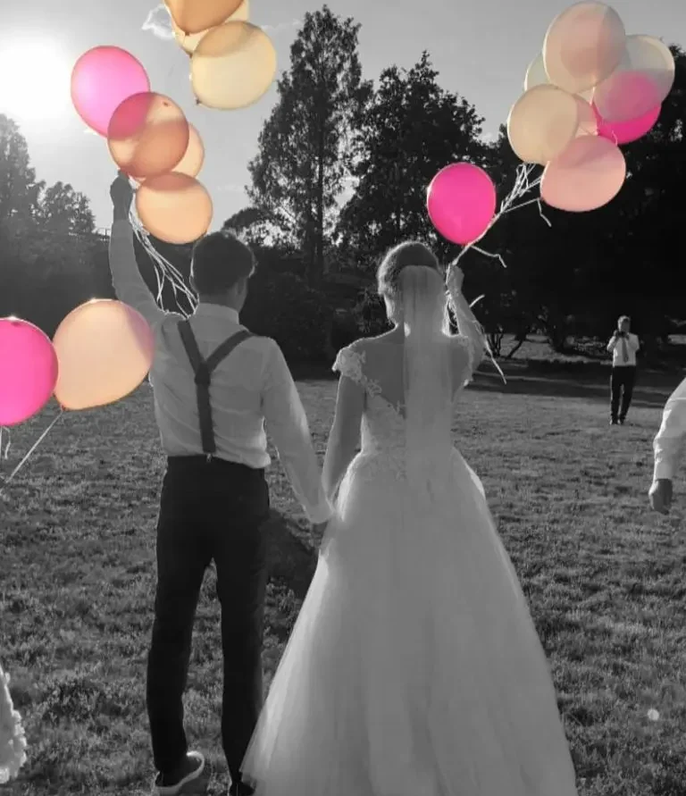 Hochzeits-DJ Altenburg Mirko Anders Hochzeitspaar hält bunten Ballons beim Sonnenuntergang auf einer Wiese.