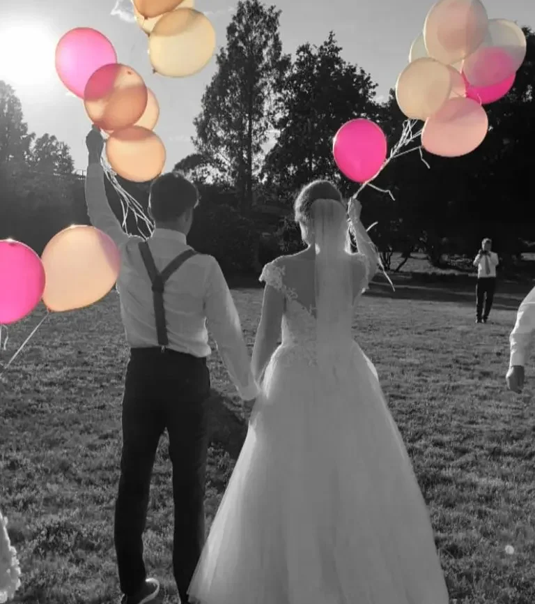 Hochzeits-DJ Bautzen Mirko Anders Hochzeitspaar hält bunten Ballons beim Sonnenuntergang auf einer Wiese.