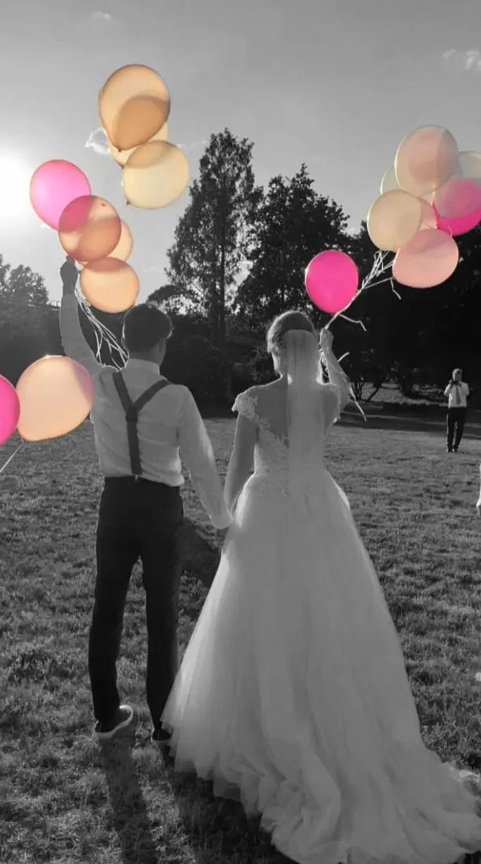 Hochzeit DJ Dresden - Hochzeitspaar hält bunten Ballons beim Sonnenuntergang auf einer Wiese.