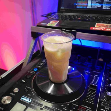Ein Glas mit einem Kaltgetränk steht auf einem DJ-Pult. Photo by DJ Mirko Anders