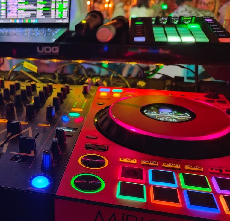 DJ-Pult mit bunten Lichtern, Plattenspieler und elektronischen Steuerungen.