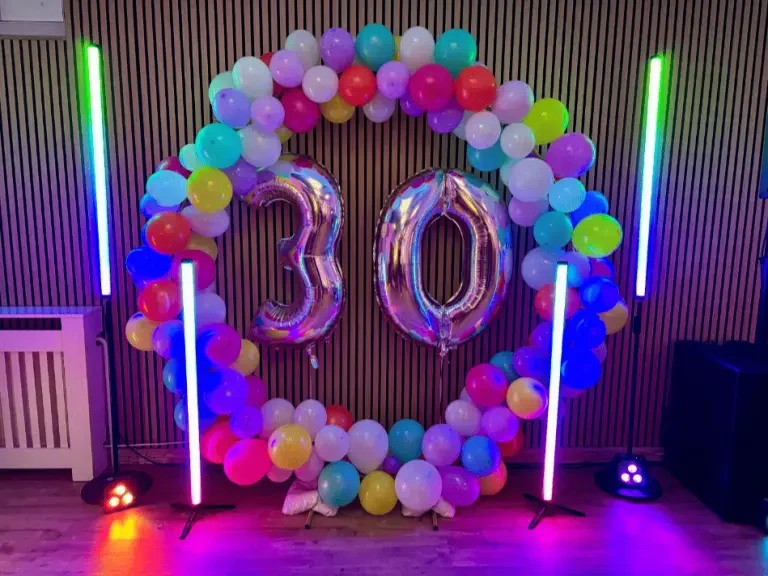 Geburtstag mit DJ Mirko Anders Party-Atmosphäre mit DJ und bunten Lichtern, Hintergrund beleuchtet in Blau und Grün.