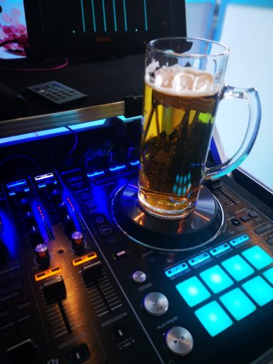 Ein Glas Bier steht auf einem DJ-Controller mit bunten Tasten und Beleuchtung. Photo by DJ Mirko Anders