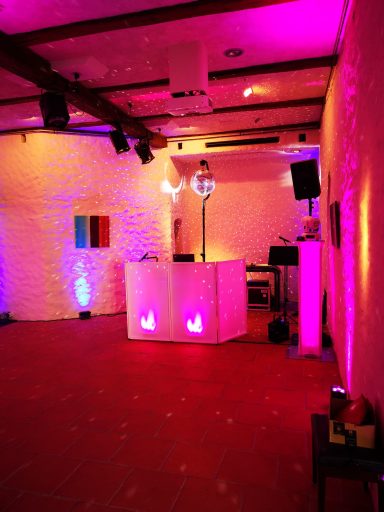 Bunter Veranstaltungsraum mit beleuchtetem DJ-Pult und farbigen Wänden. Photo by DJ Mirko Anders