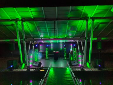 Bühne mit grünen Lichtern und Lautsprechern, bereit für eine Veranstaltung. Photo by DJ Mirko Anders