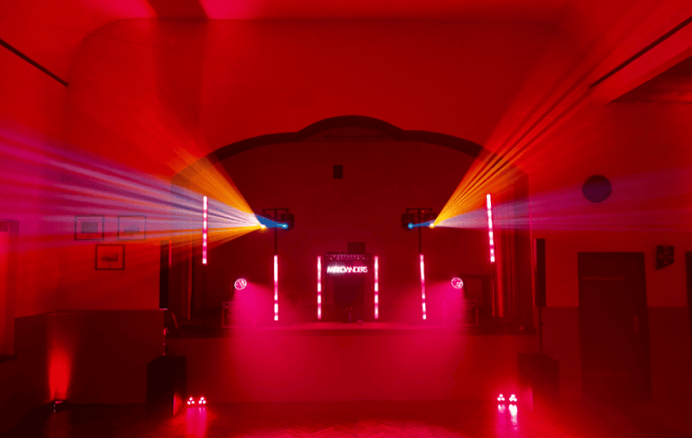 Bunte Lichtstrahlen in einem Raum mit roter Beleuchtung und futuristischem Ambiente.