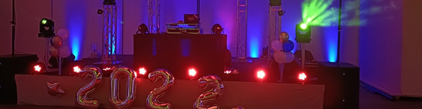 Vereinsfeier DJ Mirko Anders Bühne mit pinker und grüner Beleuchtung, Lautsprechern und stilvollem Hintergrund.