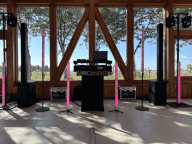 DJ-Ausrüstung mit pinken Säulen in einem hellen Raum mit Aussicht auf die Landschaft.